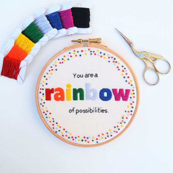 A hand embroidery hoop reading You are a rainbow of possibilities surrounded by rainbow french knots